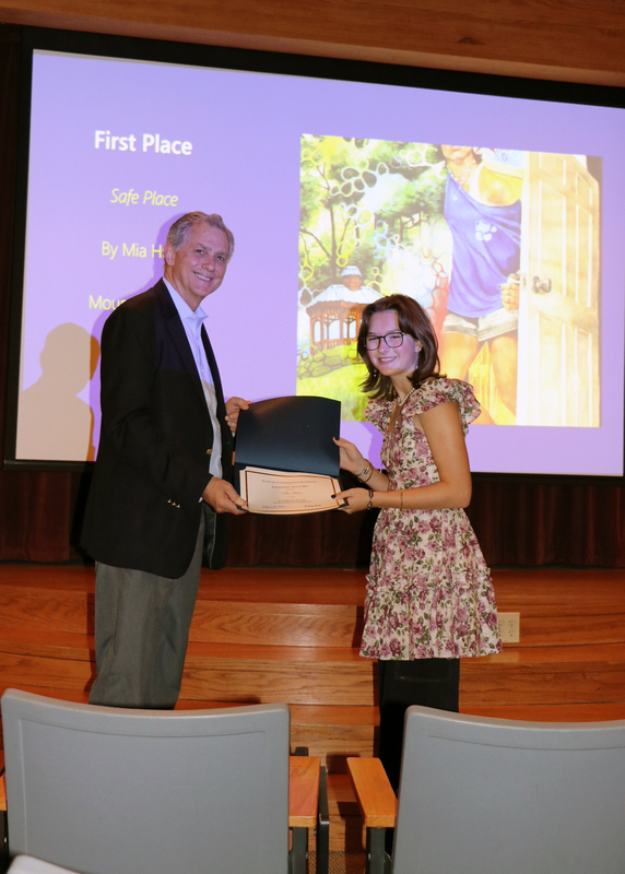 student receiving an award certificate from congressman in front of screen showing her winning artwork