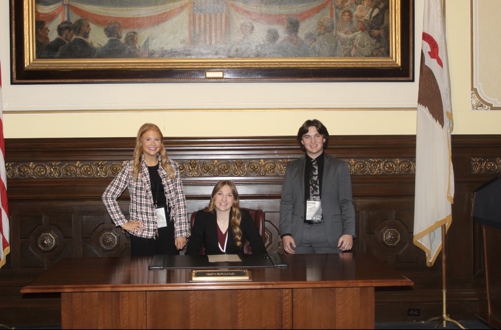 Chelsie Horner, Governor Claire Gulley and Zander Ashby deliver the first signed bill.