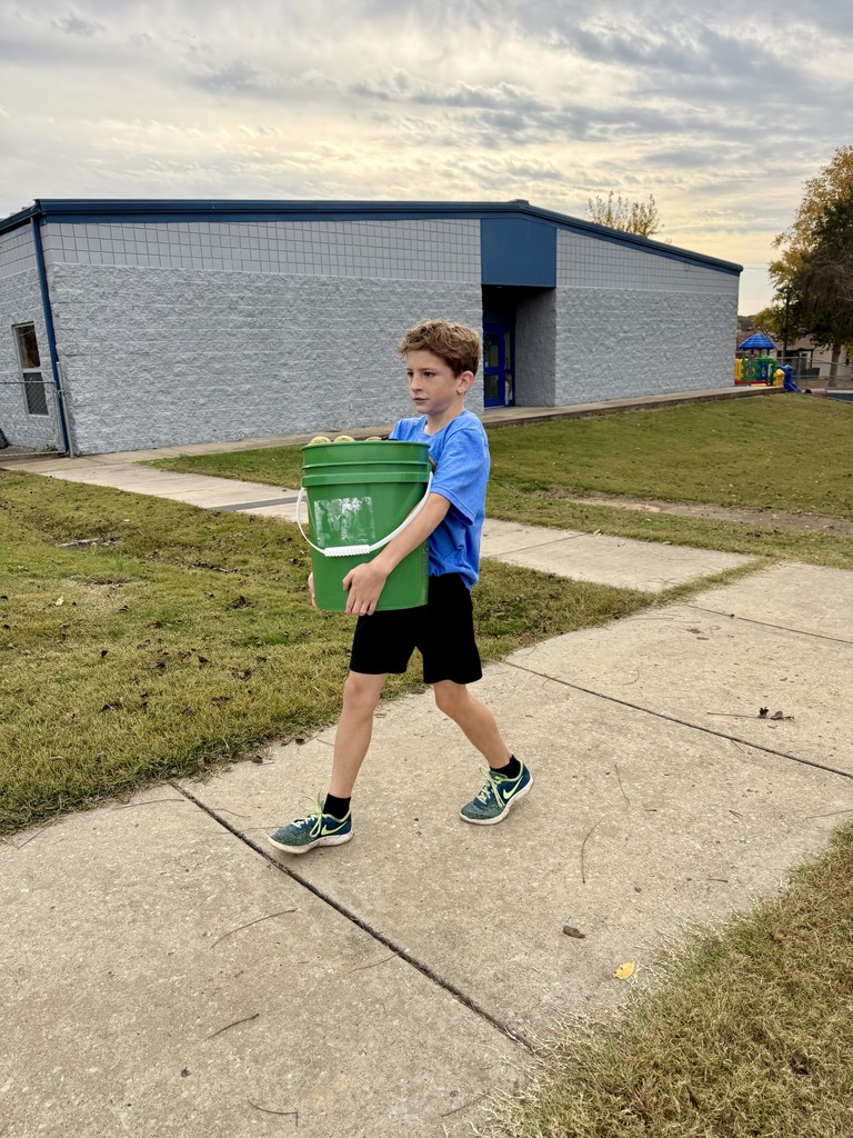 middle school boy carrying bucket of balls