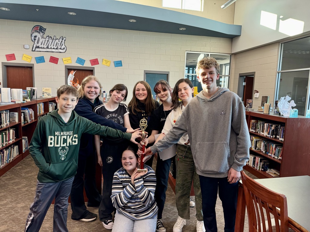 kids posing with a trophy in a library