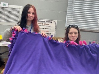 two teen girls holding a lap blanket they made