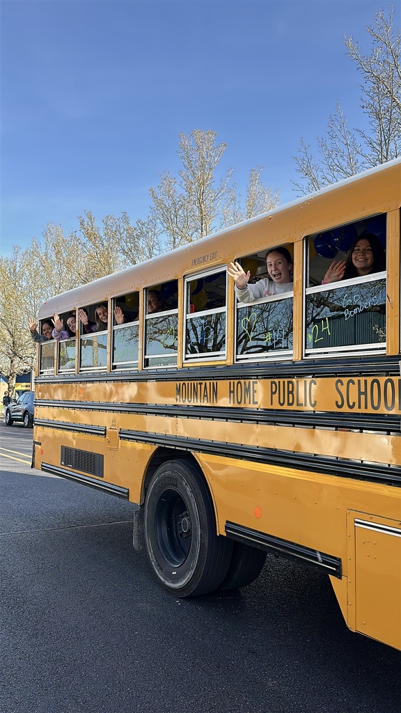 School bus with the girls basketball team looking out of the windows and waving as they drive away