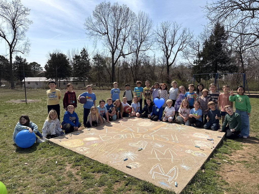 two classes of first graders posing with chalk art saying GO LADY BOMBERS