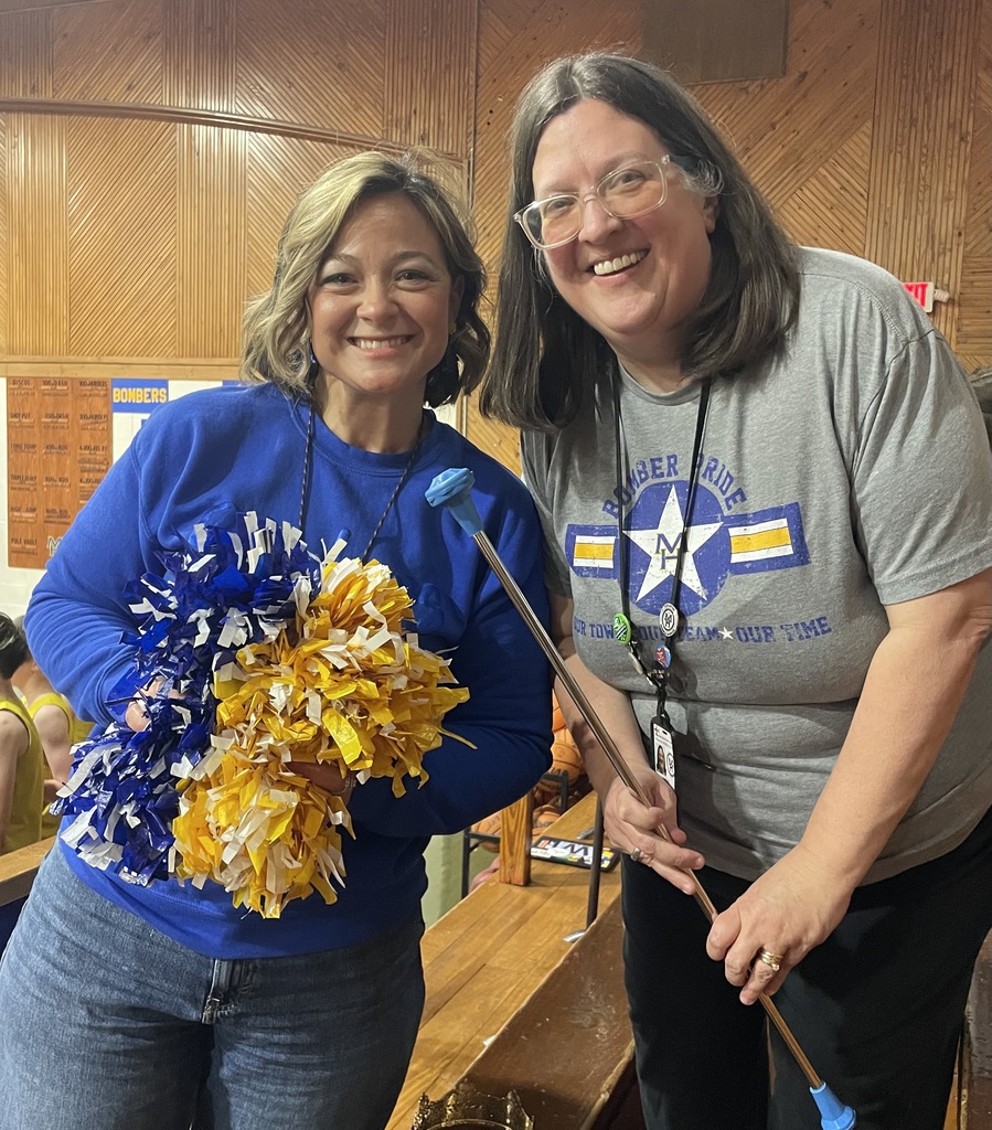 Two teachers who were on the staff cheer squad and band standing with their pom poms & baton