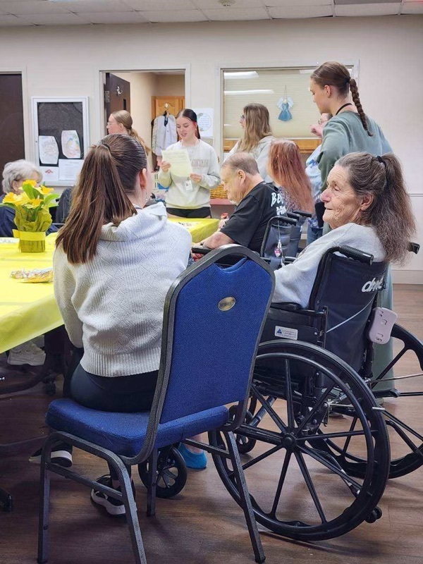 A student sits with a senior living resident. 
