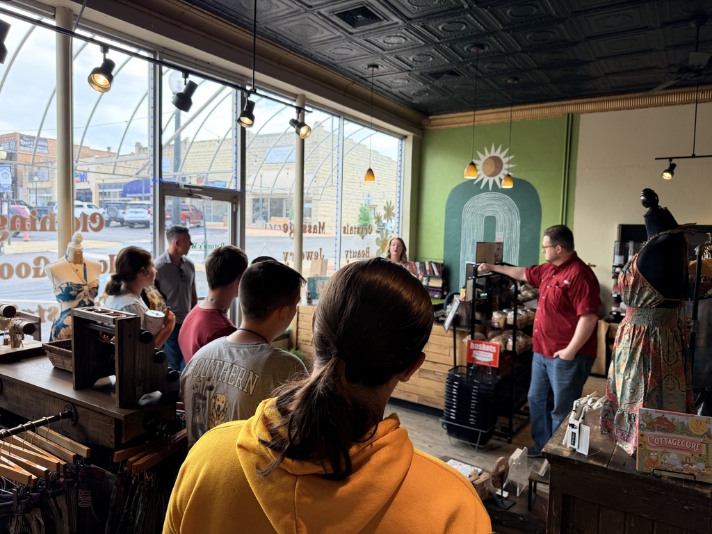 Students listening to a local business owner talk about their store. 