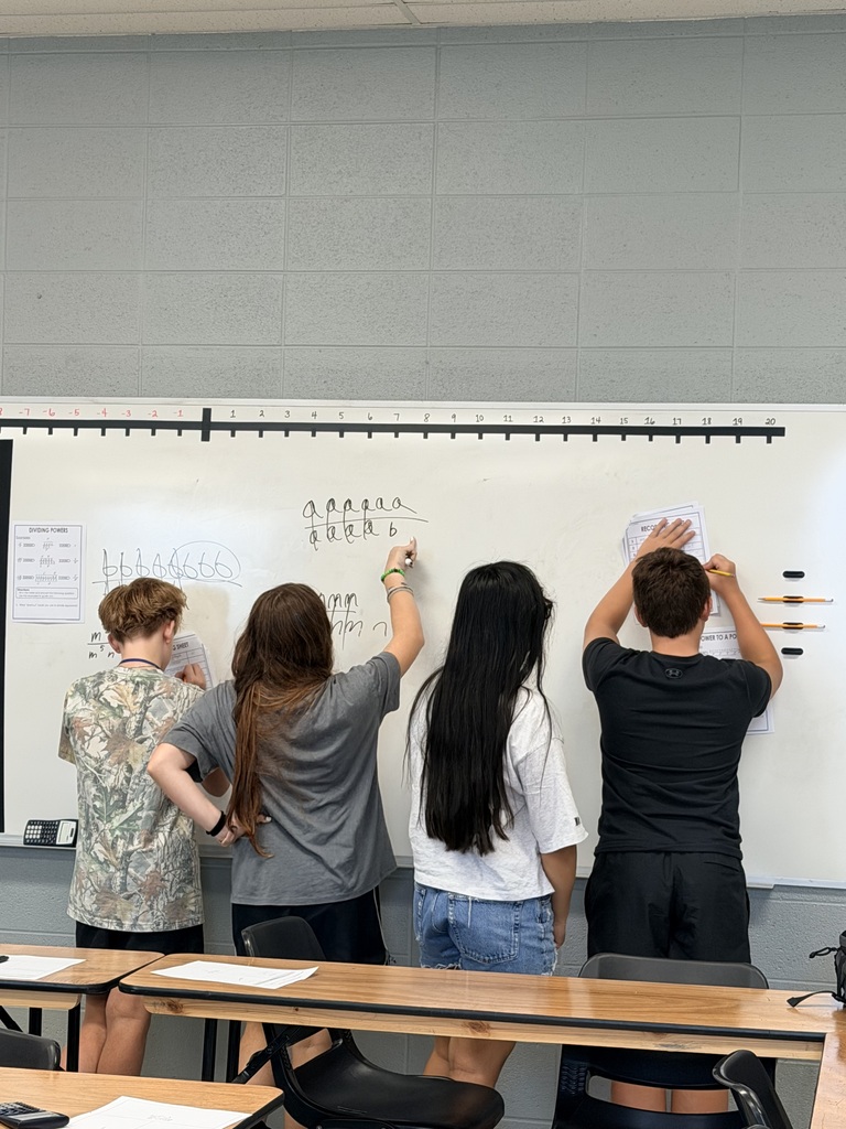4 students in Mrs. Hickman's math class working on a problem at the dry erase board 