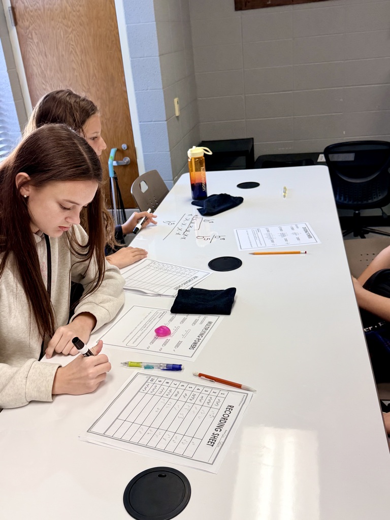 Two female students working on math at dry erase tables