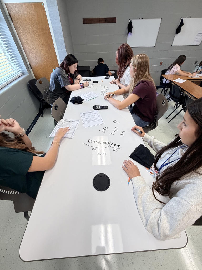 5 female students working on math problems at dry erase tables 