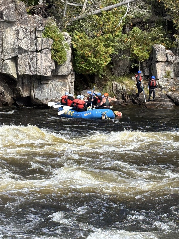 Marshwood High School students navigating a river in a blue raft on a rafting trip
