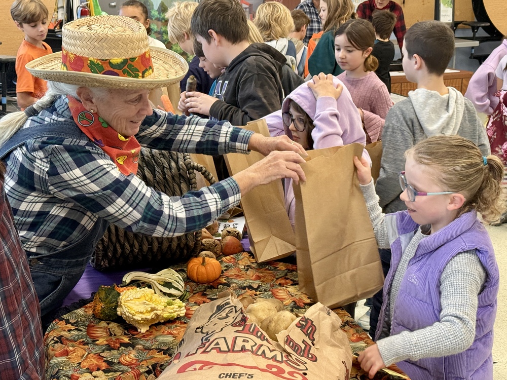 A food service team member at Jerry Burnell Great Works School bags vegetables for a student during a school farmers market Oct 22, 2026