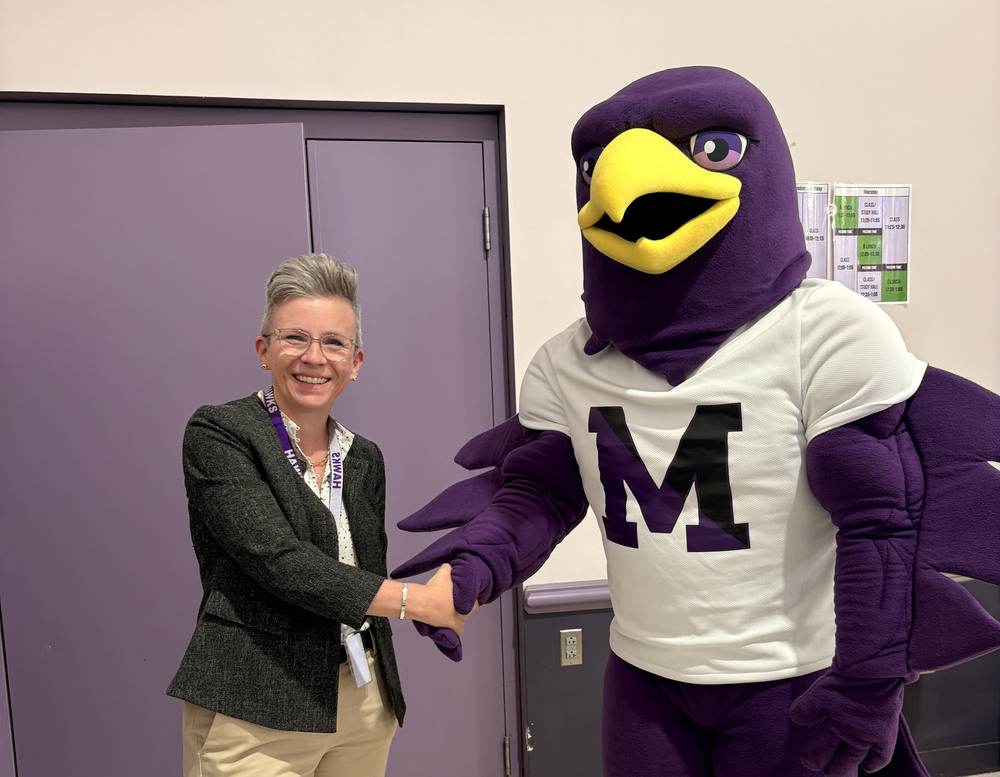 on the left, Marshwood Superintendent Dr. Caroline Arakelian shakes hands with the Marshwood Hawk mascot standing on the right.