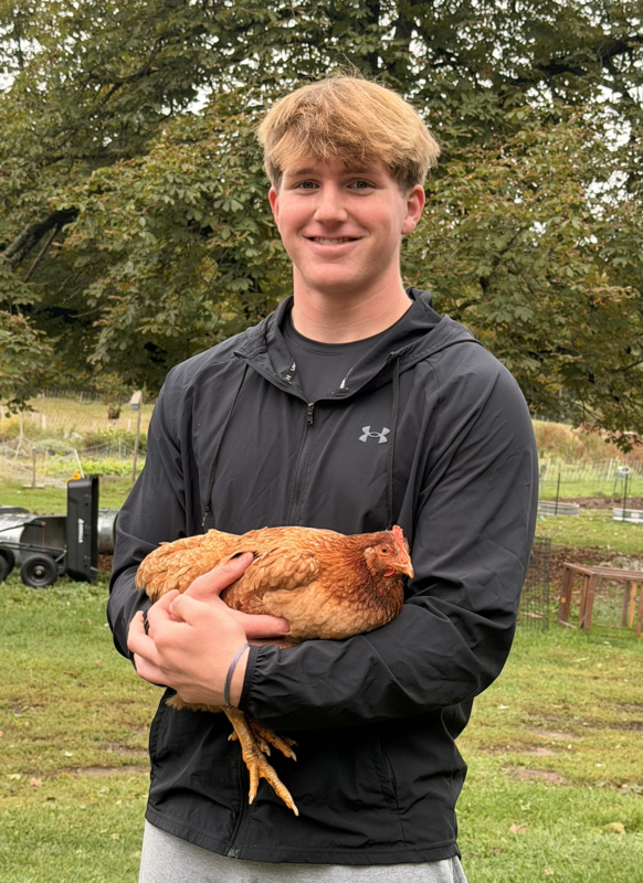 A student from Marshwood High School holds a chicken as part of a class farm trip sponsored through a recent grant