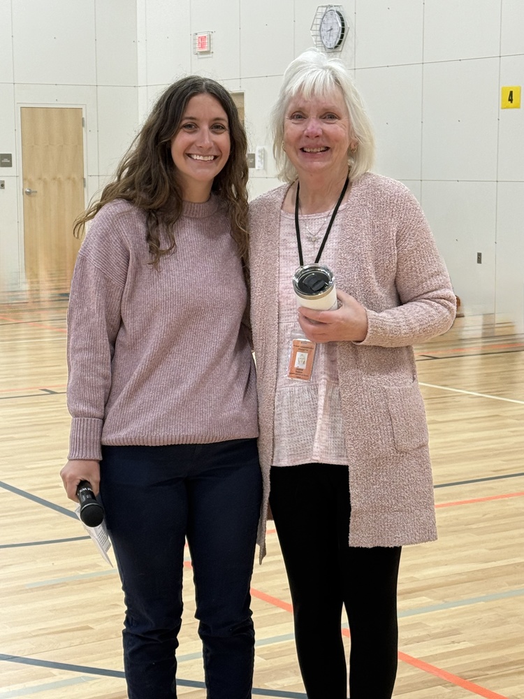 Staff members holding cup and microphone in school gym