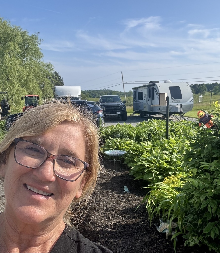 Teacher outside with River Hawk plushie in front of garden