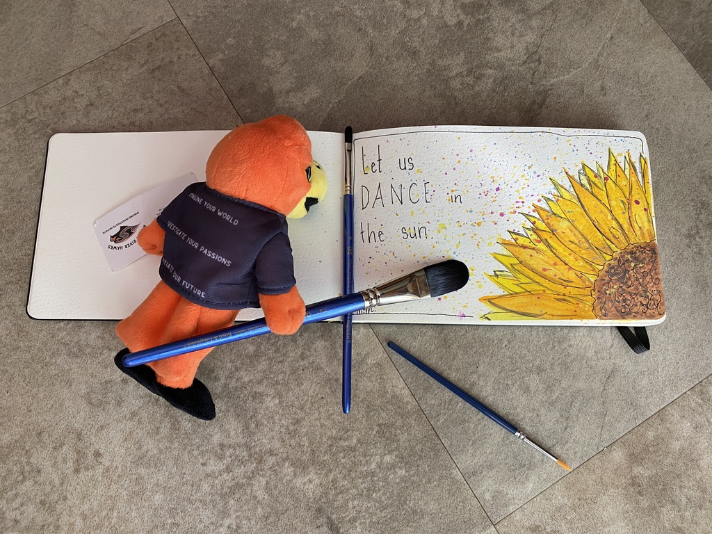 River Hawk Plushie with paint brush and flower painting that states "let us DANCE in the sun"