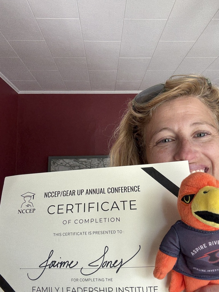 Teacher with River Hawk plushie and leadership conference certificate