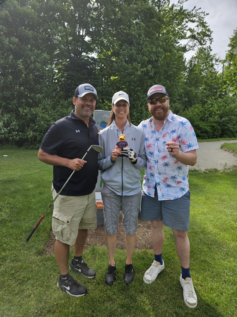 Teachers outside with River Hawk plushie on gold course