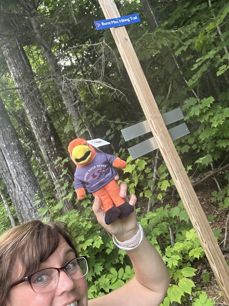 teacher with river hawk plushie on a hiking trail