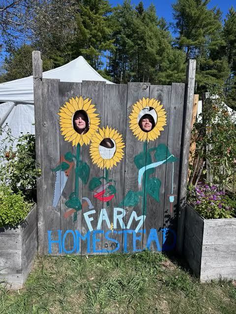 Students outside standing behind a sunflower photo wall, that reads Farm Homestead.