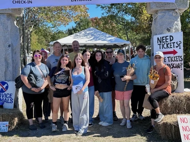 Students and staff outside taking a group photo at the entrance of the Common Ground Fair