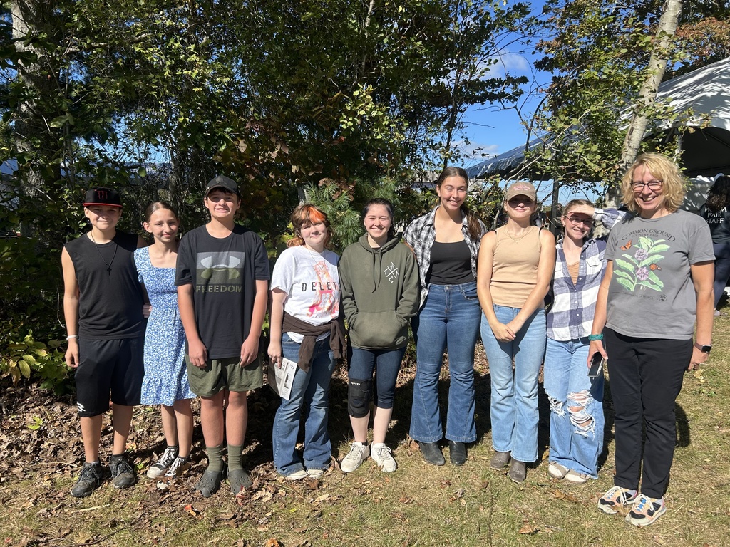 Students and teacher outside in front of trees