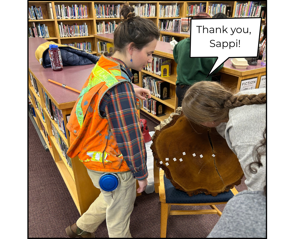 student and forester looking at tree trunk in library