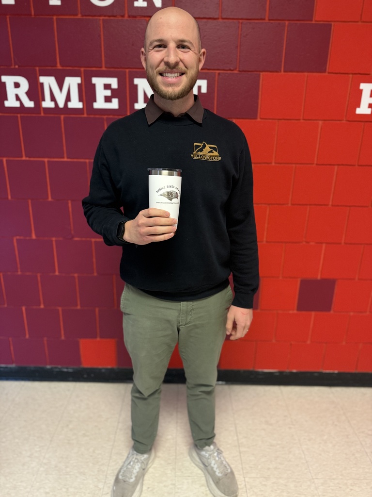 teacher holding cup in school hallway