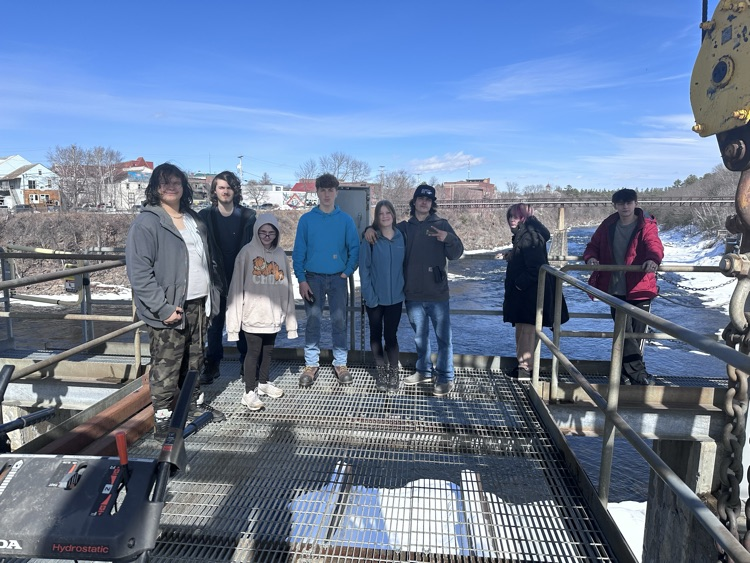 a group of students posing above the log sluice at the dam