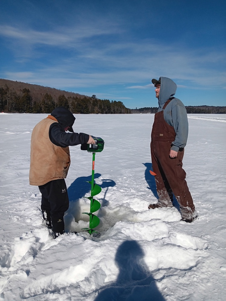 2 boys drilling holes for ice fishing
