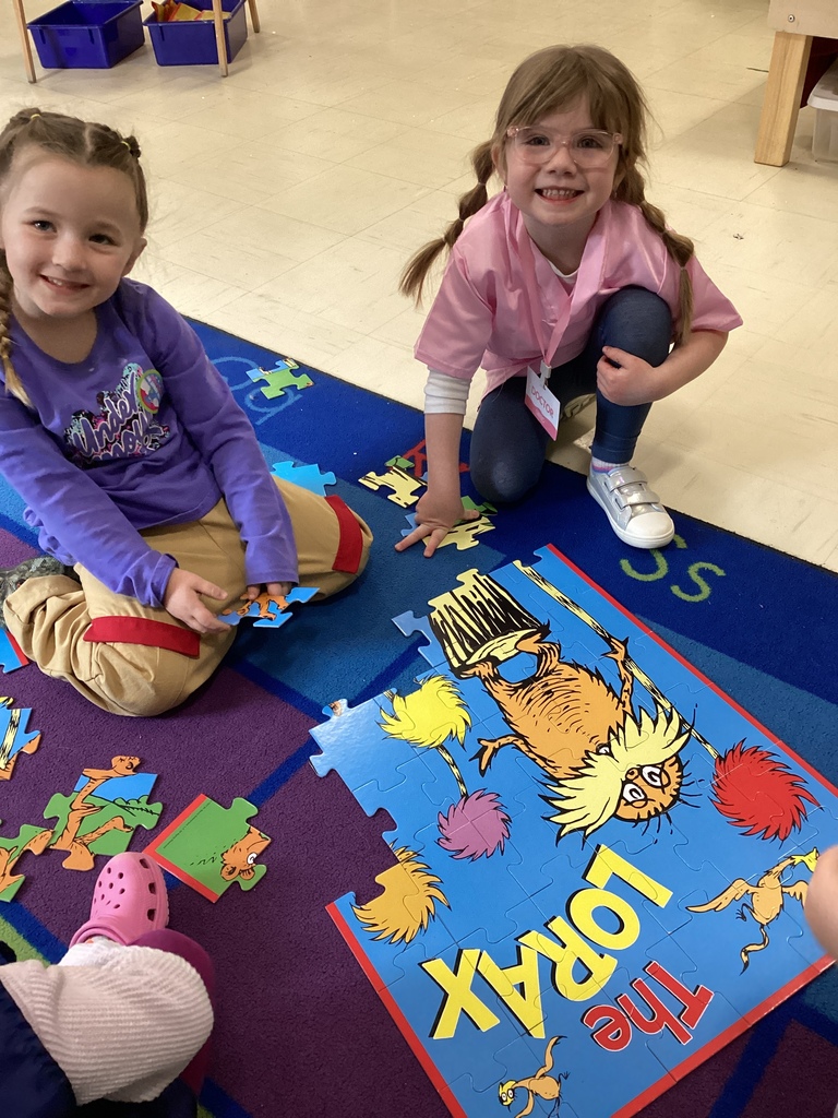 Two girls completing a puzzle on the floor.