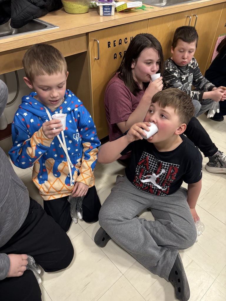 Two boys drink from white plastic cups.
