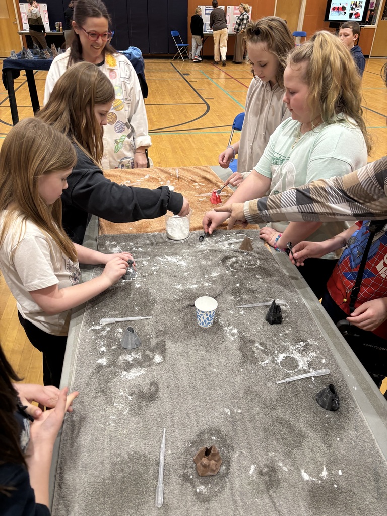 Students around a table with pipettes and mini volcanos.