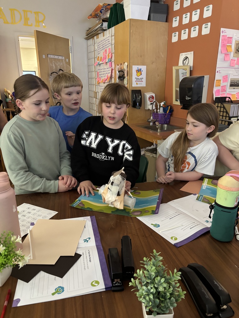 Students gather around table to demonstrate a project.