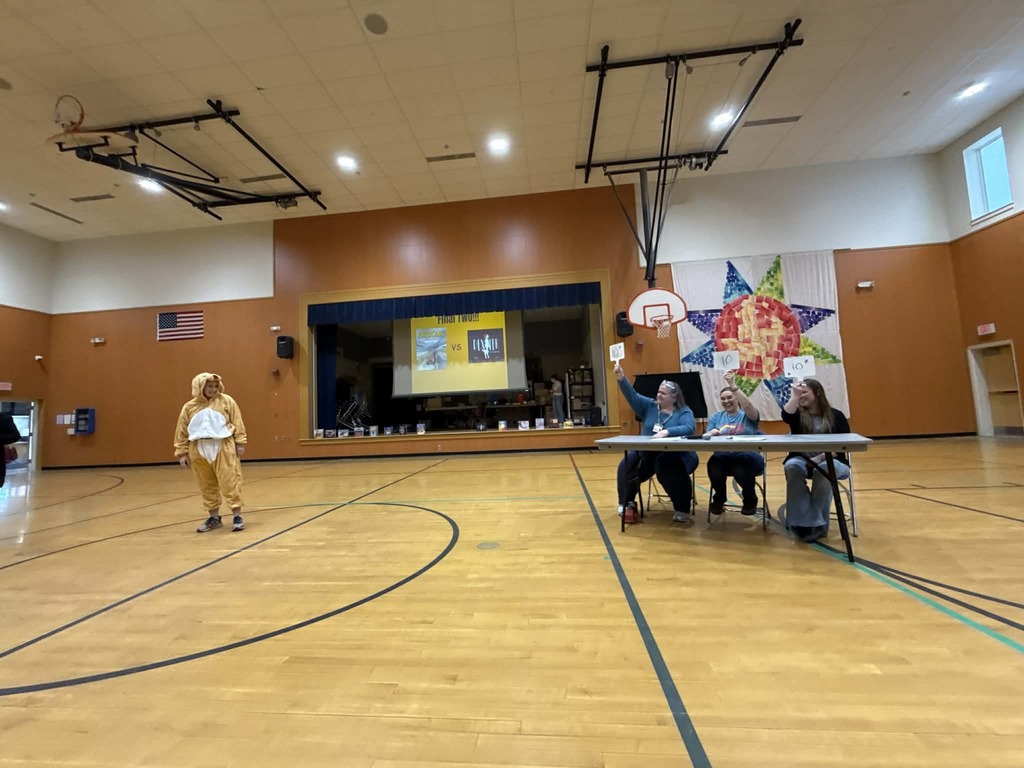 Judges hold scores for person dressed in dog costume. 