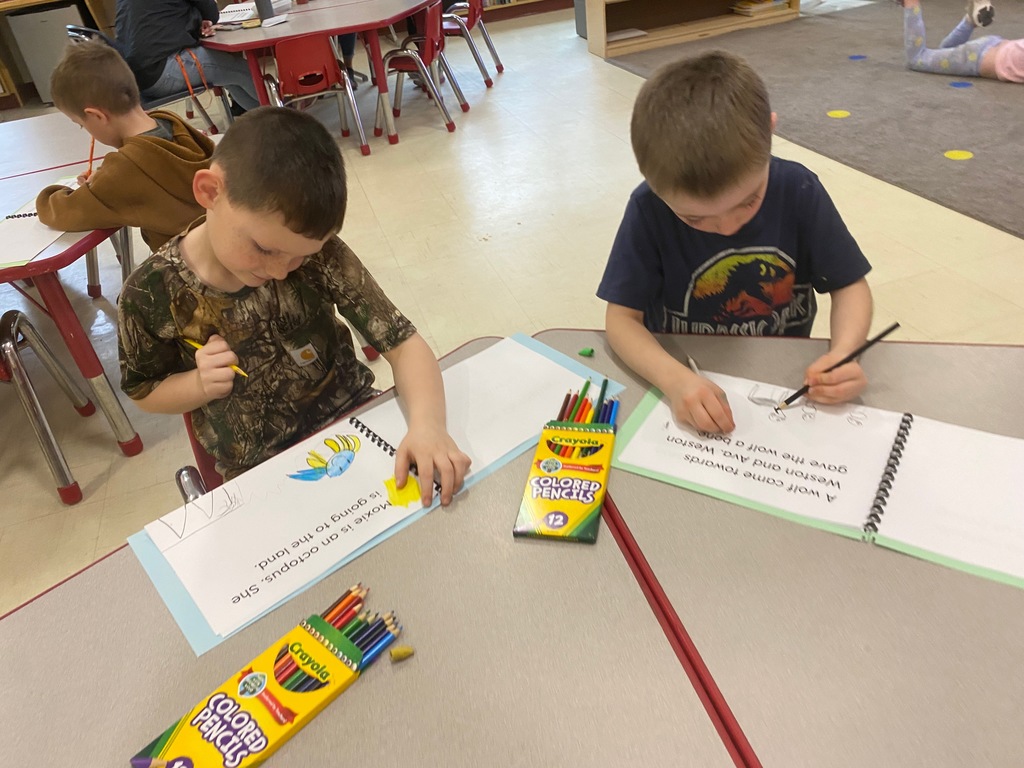 Two boys work at a table on their papers.
