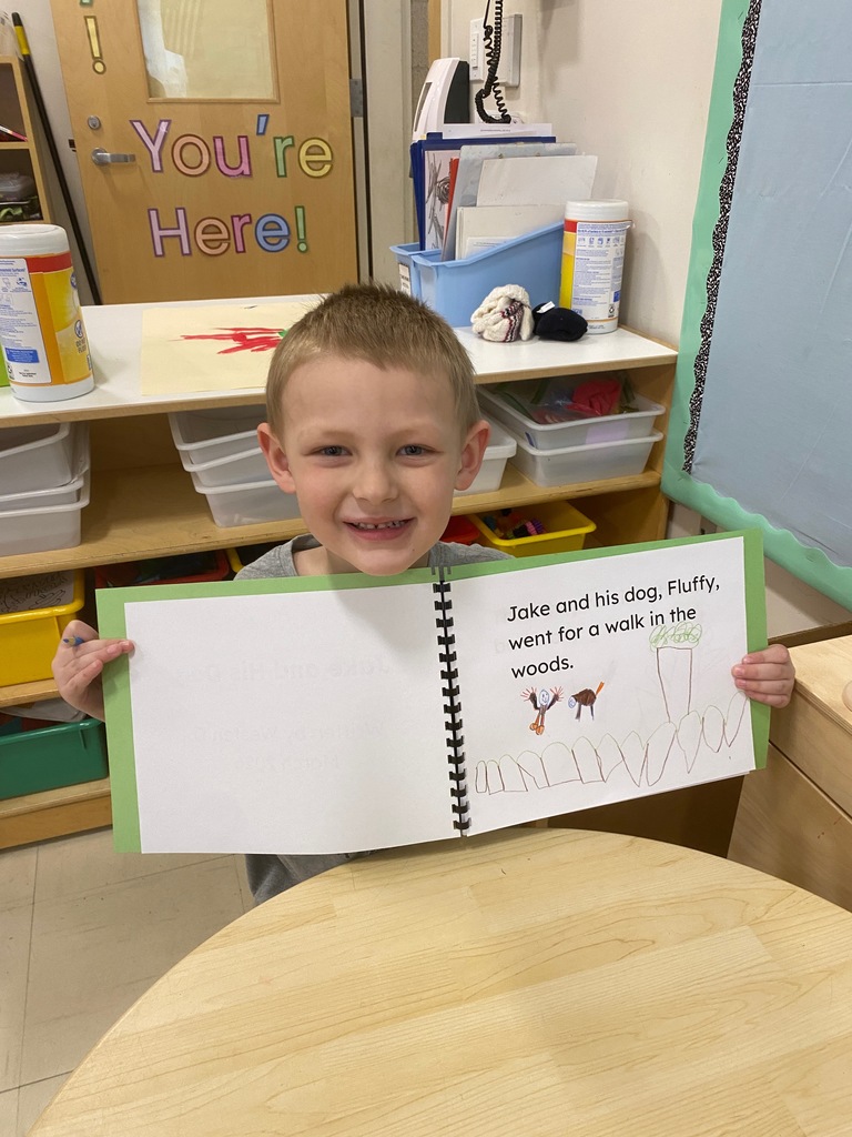 A boy holds up his book.