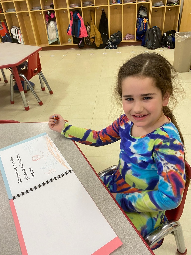 A girl smiles while sitting by her work.