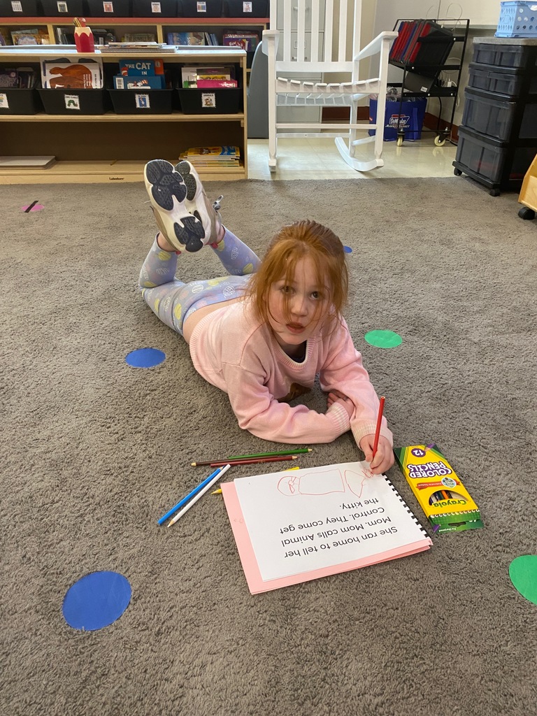 A girl lays on the rug while working.
