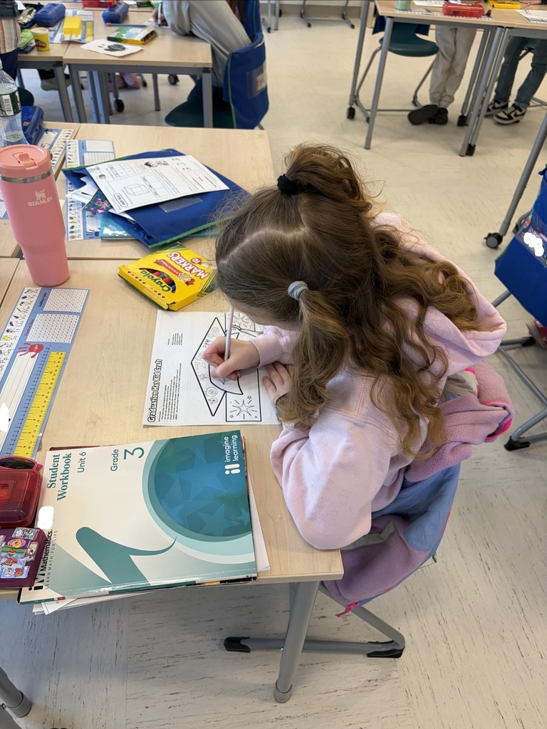 student coloring graduation cap at desk in school classroom