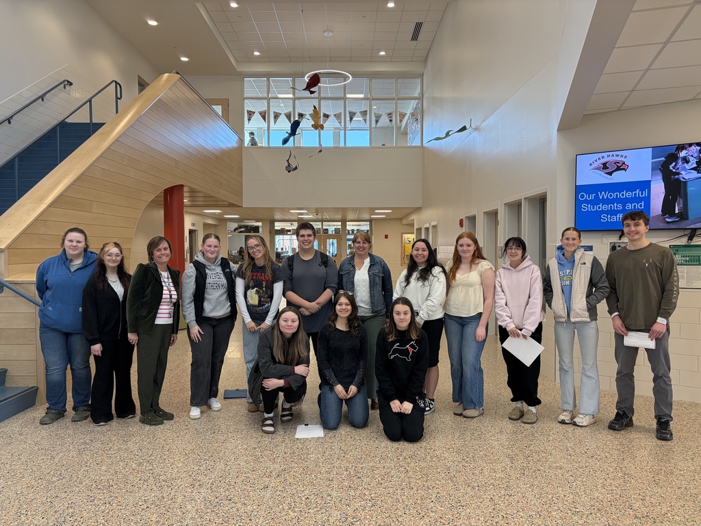 students and admin smiling for photo in hallway