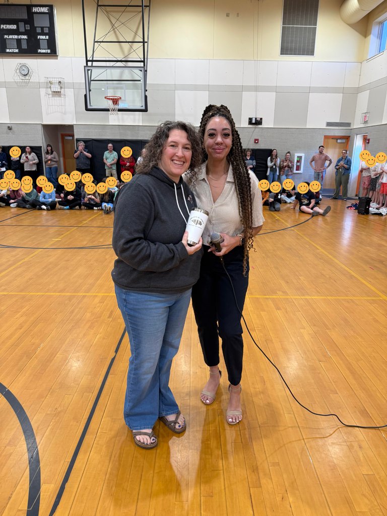 student receiving award in school gym in front of students and staff