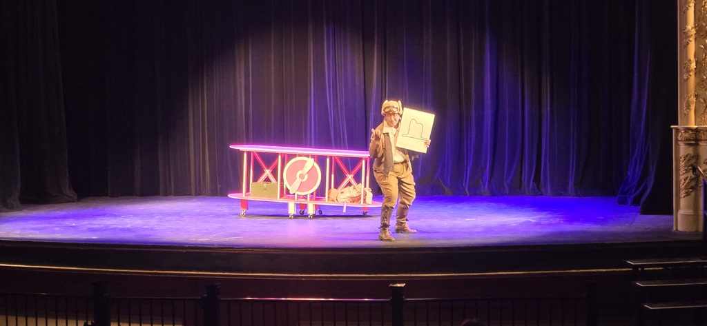 A man stands in front of a airplane model on stage.
