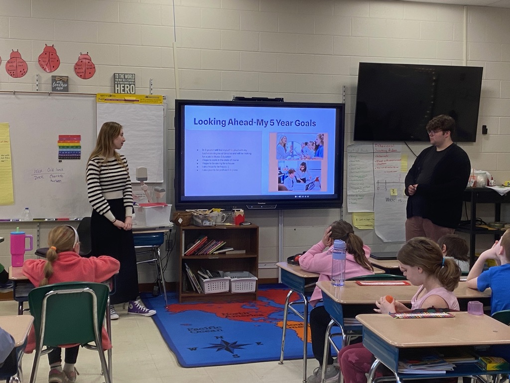 Two students stand next to a projected screen.