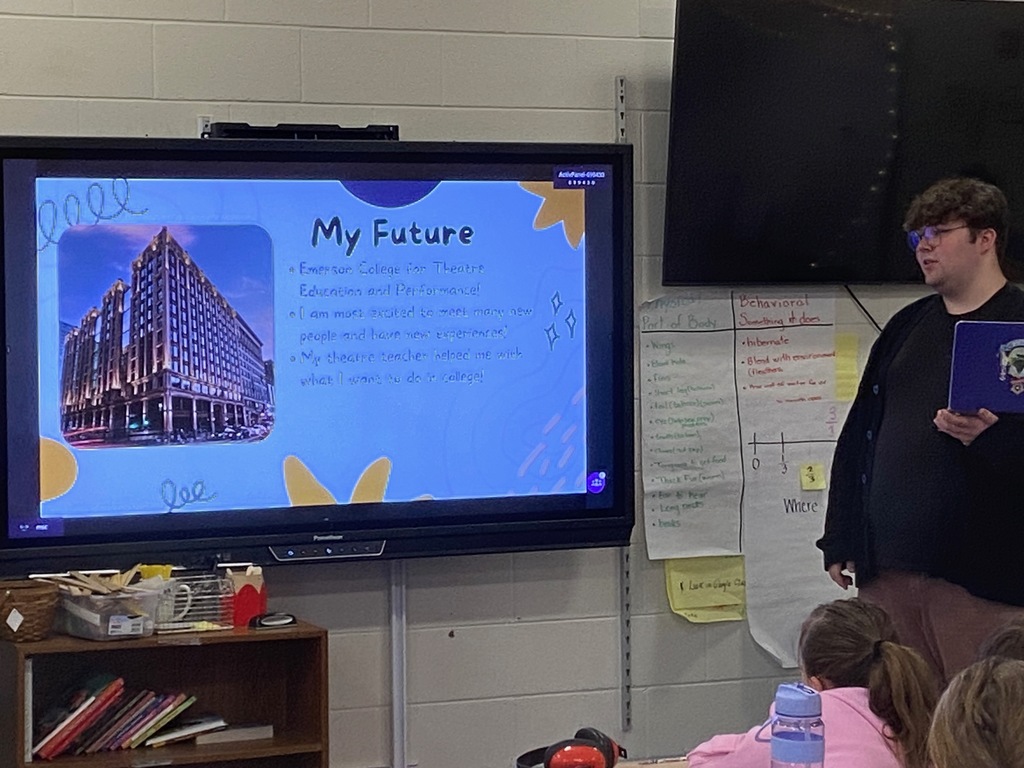 A student stands next to a projected screen. 