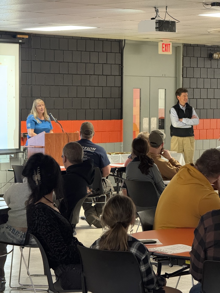 Speakers in front of crowd sitting in cafeteria