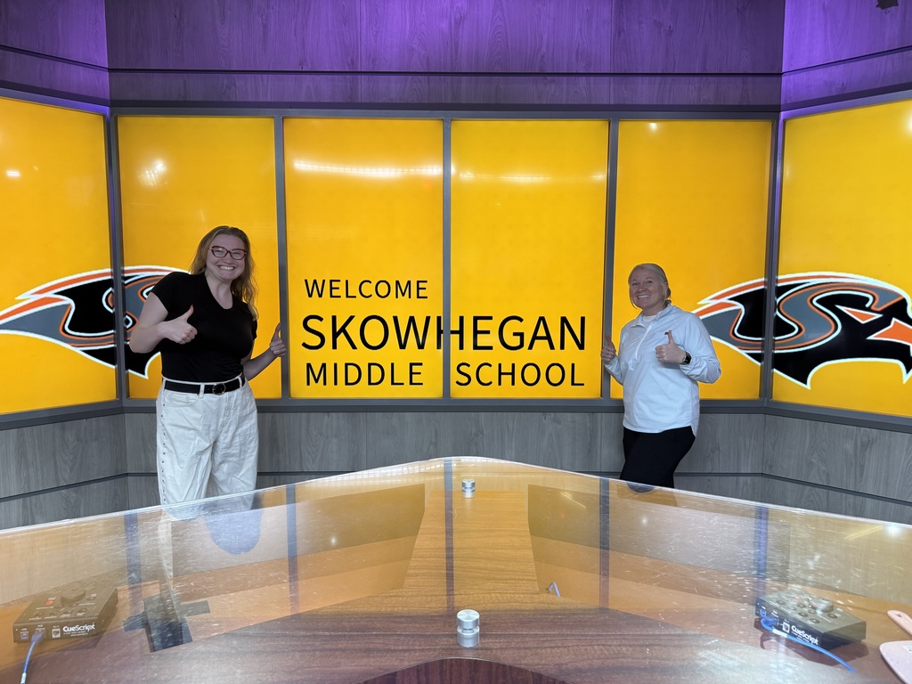 teachers behind news desk, in front of sign welcoming skowhegan middle school