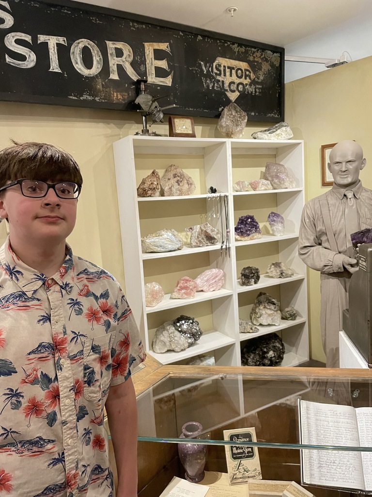student standing in front of mannequin and display case and shelves of minerals and gems in museum gift shop setting