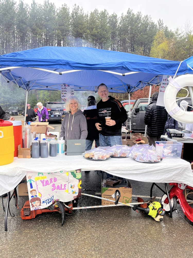 staff smiling behind a table of food they are selling at the yard sale