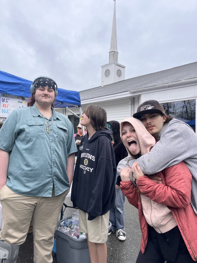 4 students posing in front of yard sale booth